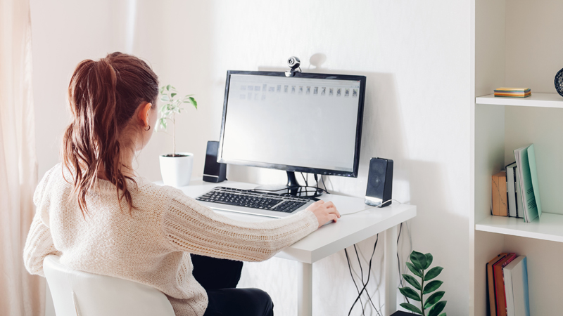 Mulher sentada em frente a um computador em teletrabalho